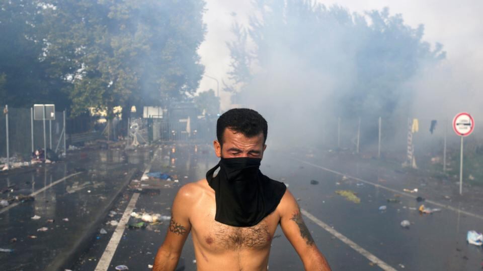 Hungarian riot police in the background fire tear gas and water cannon at the border crossing with Serbia at Roszke, Hungary, September 16th, 2015. Photograph: Stoyan Nenov/Reuters