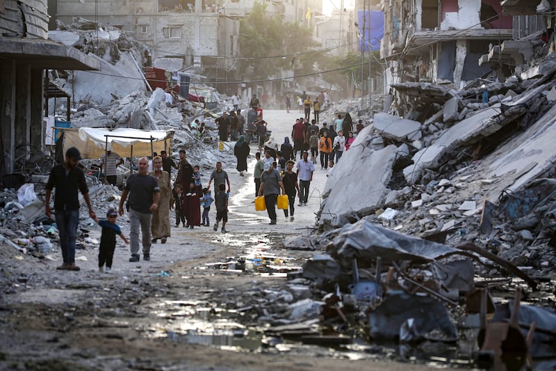 Palestinians displaced by the Israeli air and ground offensive on the Gaza Strip, walk through a streak of sewage flowing into the streets of Khan Younis. Photograph: Jehad Alshrafi/AP