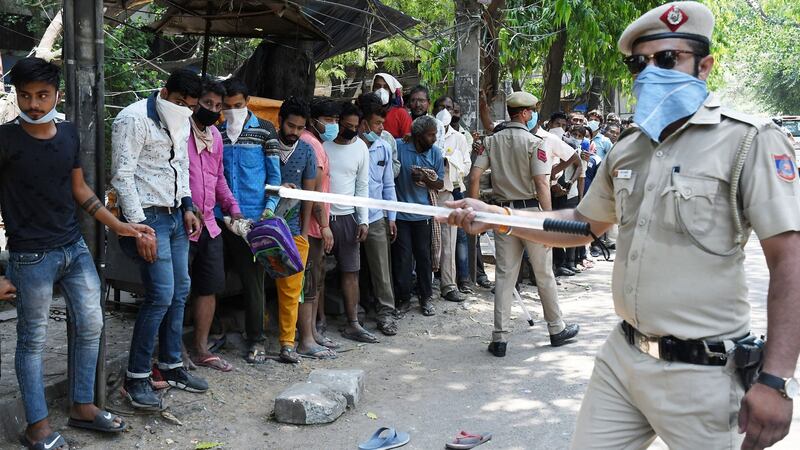 Indian police officers try to enforce social distancing as people queue for a liquor shop in New Delhi. Photograph: EPA/STR