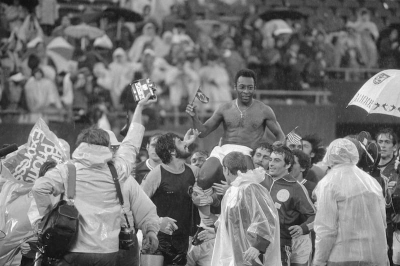 Pelé is carried off the field by members of both teams (Cosmos and Santos) while holding both US and Brazilian flags. Photograph: Bettmann/Bettmann Archive