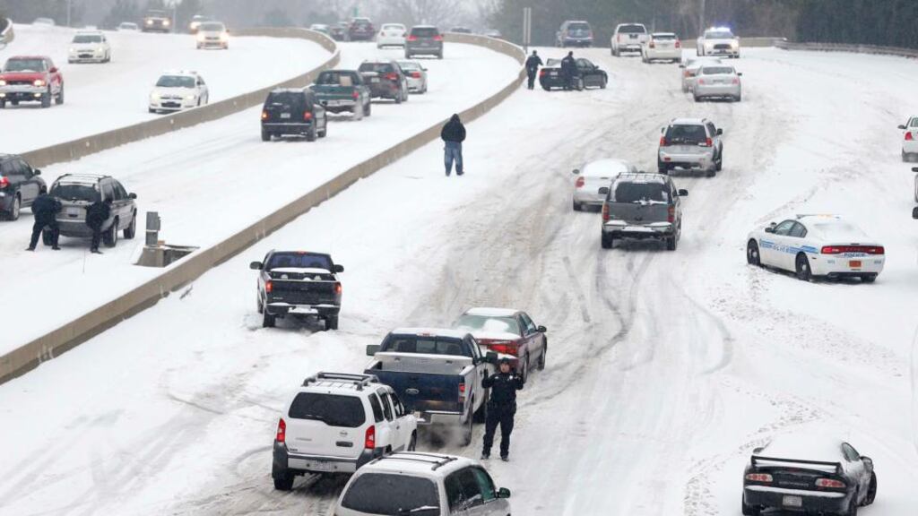Police  work to assist motorists as they attempt to drive up a hill covered in snow in Charlotte, North Carolina, yesterday. Photograph: Chris Keane/Reuters