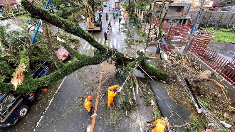 Emergency workers clear a toppled tree in the town of Tigaon, Camarines Sur, in the Philippines. Photograph: EPA