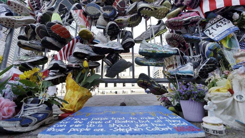 Running shoes hang on a fence at a makeshift memorial near the Boston Marathon finish line in Boston’s Copley Square.