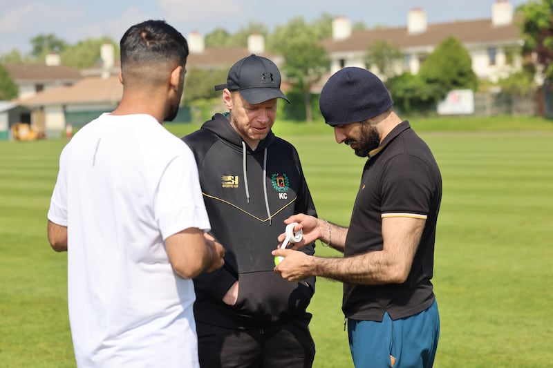 Kenny Carroll, from Railway Union Cricket Club, getting a lesson in taping a tennis ball from Kamran Kochai and Adnan Khan, as the club invited homeless asylum seekers to play cricket in Sandymount, Dublin. Photograph: Dara Mac Dónaill