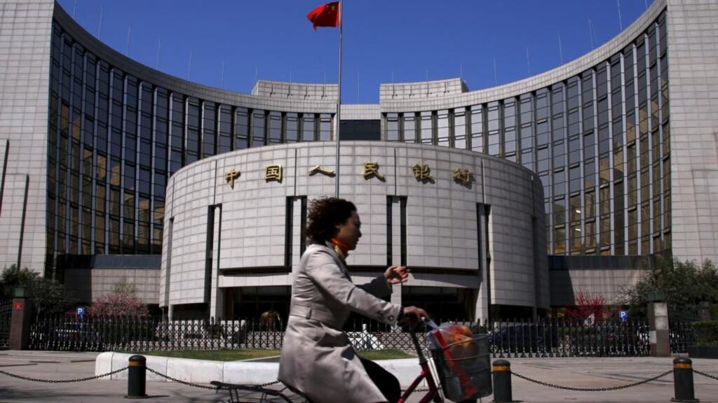 A woman rides past the headquarters of the People’s Bank of China. Chinese stocks edged lower on Monday as an interest rate cut by the central bank failed to impressed investors. (Photograph: Petar Kujundzic/Reuters)