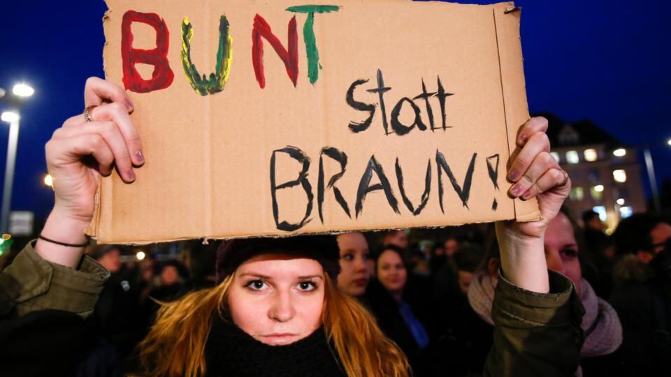 A counter protester holds up a sign during a demonstration called by anti-immigration group Pegida. The sign reads, “colourful instead of brown”. Photograph: Hannibal Hanschke/Reuters