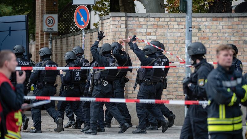 Police walk along the wall to a Jewish cemetery near the scene of a shooting that has left two people dead in Halle, Germany. Photograph: Jens Schlueter/Getty Images