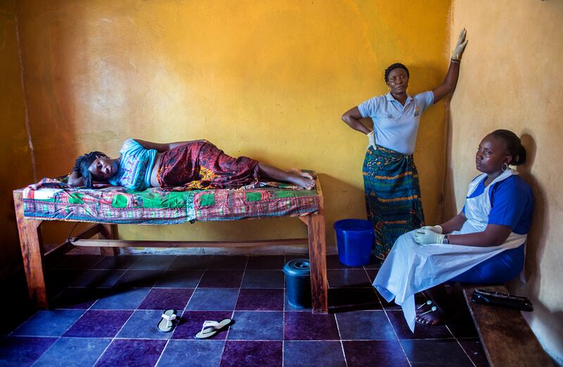 Kadiatu Tuayemie (25) lies in labour under the watchful eye of community health worker Adana Kajue and Theresa Mansaray, midwife in training, at the Kahekay MCH Peripheral Health Unit in Junctonil, Bonthe, Sierra Leone, February 2016. Photograph: Brenda Fitzsimons