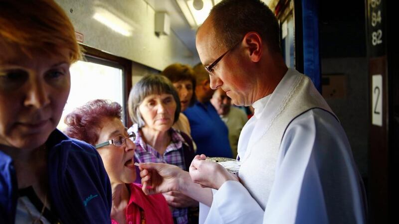 A priest distributes Holy Communion to pilgrims on a train headed towards Rome to witness the canonisations of Pope John XXIII and Pope John Paul II at the Vatican. Photograph: Kacper Pempel/Reuters.