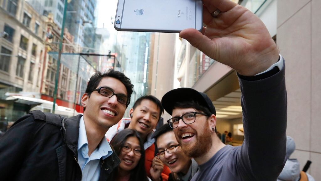 An Apple employee taking a ‘selfie’ photograph of some people with the new iPhone 6s phone, as they stand in a queue inside the Apple store in Sydney, Australia, the first day of its sale worldwide. On Monday Apple said it had sold 13 million iPhone 6s and iPhone 6s Plus mobile phones worldwide, a new record for the company. (Photograph: DAVID MOIR/EPA_