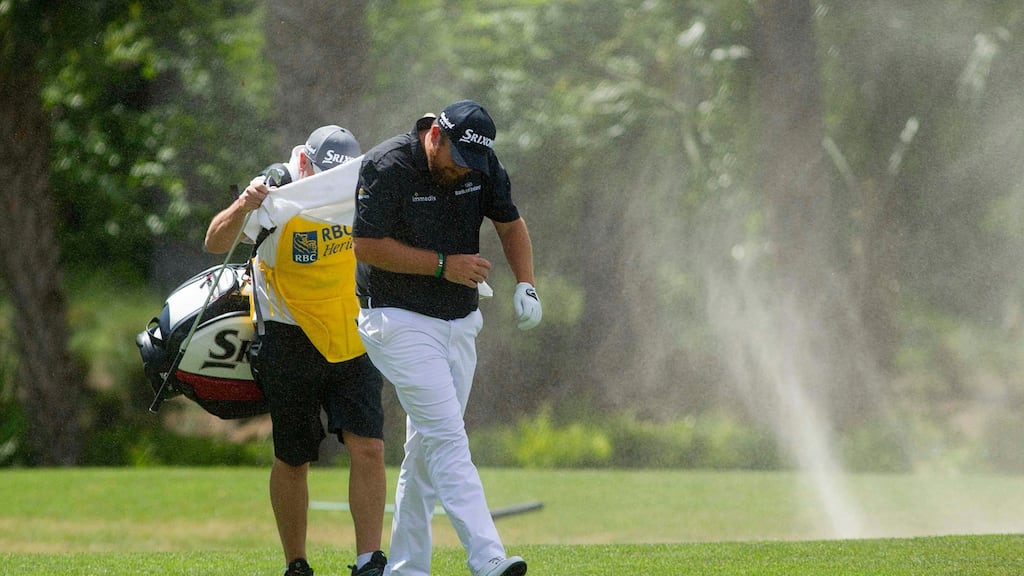 Shane Lowry and his caddie are caught in a small sand vortex on the fairway of the fifth hole during the final round of the RBC Heritage tournament at Harbour Town Golf Links. Photograph:  Joshua S Kelly-USA TODAY Sports