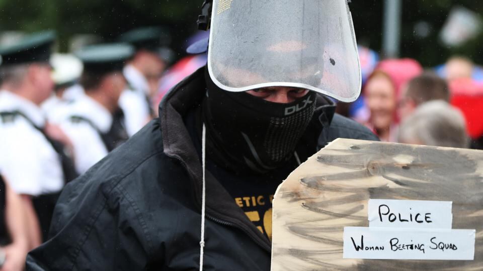 A loyalist supporter dressed as a riot police officer approaches police as they await an Orange Order parade on Crumlin Road. Photograph: Brian Lawless/PA Wire
