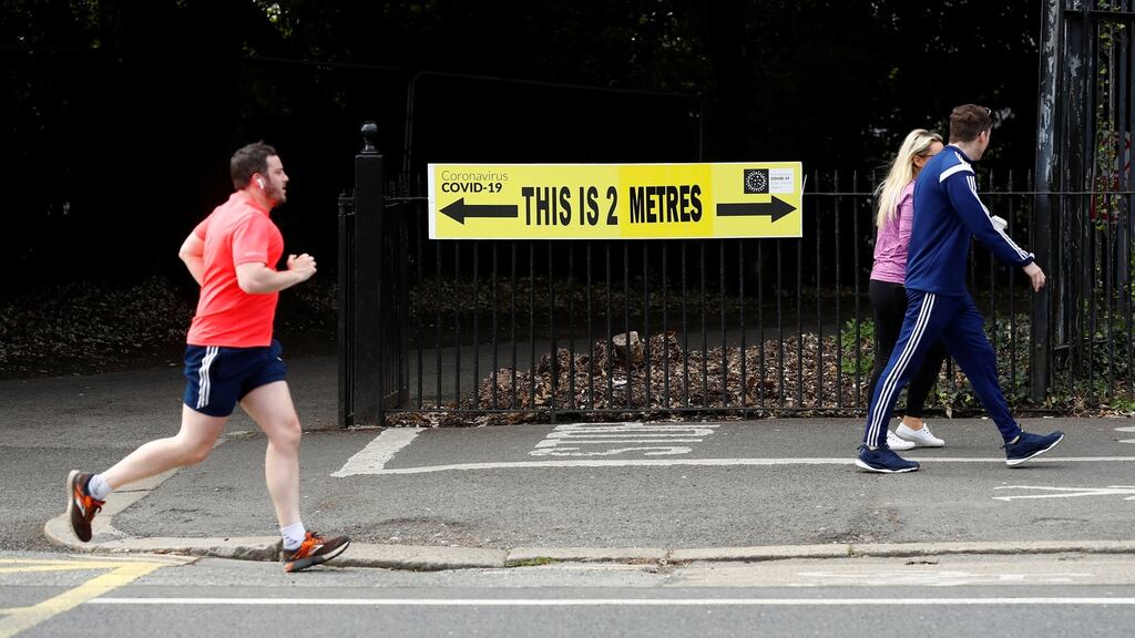 People are seen jogging past a social distancing sign in the Phoenix Park in Dublin last week. Photograph: Jason Cairnduff/Reuters
