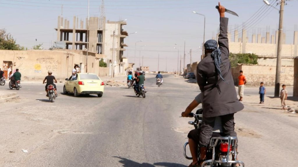 A man holds up a knife as he rides on the back of a motorcycle touring the streets of Tabqa city with others in celebration after Islamic State militants took over Tabqa air base, in nearby Raqqa city on Sunday. Photograph: Reuters )