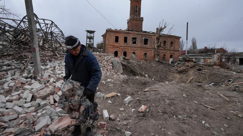 A man holds fragments of a rocket launched by the Russian forces at night, with a rocket crater behind him, in the center of Kharkiv, Ukraine. Photograph: Efrem Lukatsky/AP