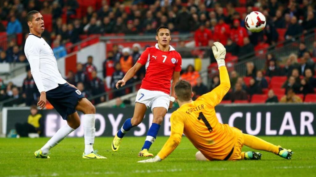 Chile’s Alexis Sanchez clips the ball past scores past England’s goalkeeper Fraser Forster to score his second goal while Chris Smalling looks on during last night’s international friendly at Wembley Stadium in London. Photo: Darren Staples/Reuters