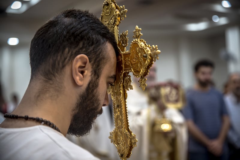 A man holds a cross to his forehead during a service in the Mar Elias church in Damascus