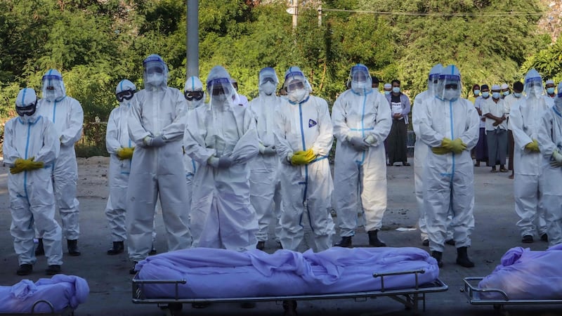 Volunteers wearing personal protective equipment pray in front of bodies of people who died from Covid-19 during their funeral at a cemetery in Mandalay. Photograph: AFP via Getty Images