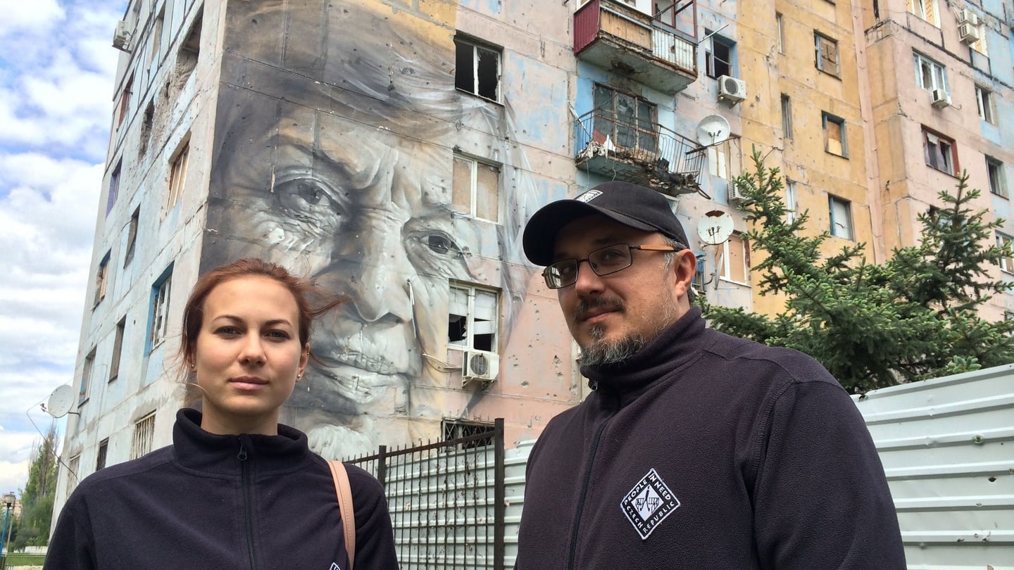 Maria Lozan and Sergei Sayenko of NGO People in Need stand in front of a mural of a local schoolteacher in the frontline Ukrainian town of Avdiivka. Photograph: Daniel McLaughlin