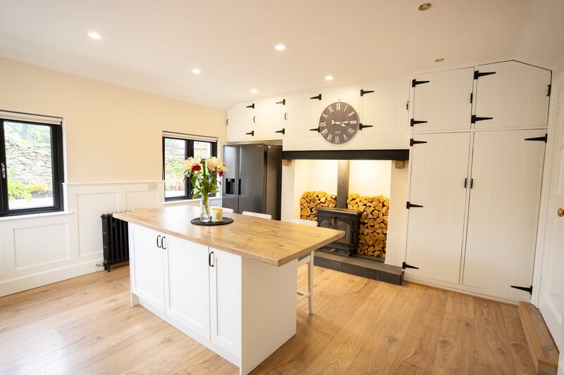 The owners kept the panelled cupboards that had been in place, painting them white with black hinges. These cupboards frame the large hearth where there is a wood-burning stove.