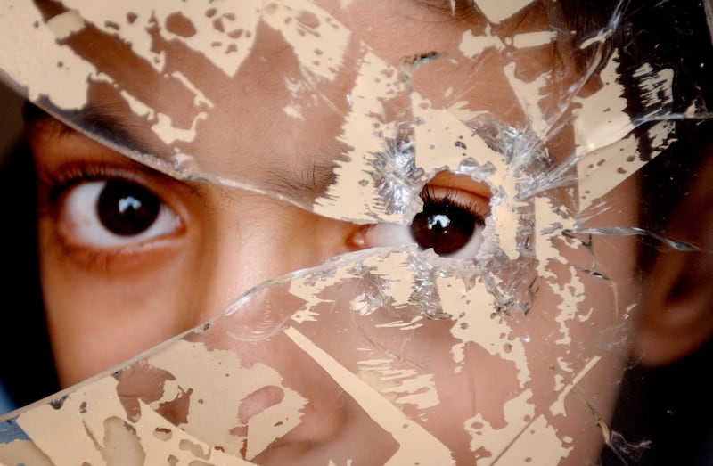 An example of the photography of Richard Mills: Twelve-year-old Shaheen Al Edany looking through a bullet hole. The bullet killed his father Waisam who tried to protect Shaheen from US troops shooting in the street. Photograph: Richard Mills/Times Newspapers Ltd