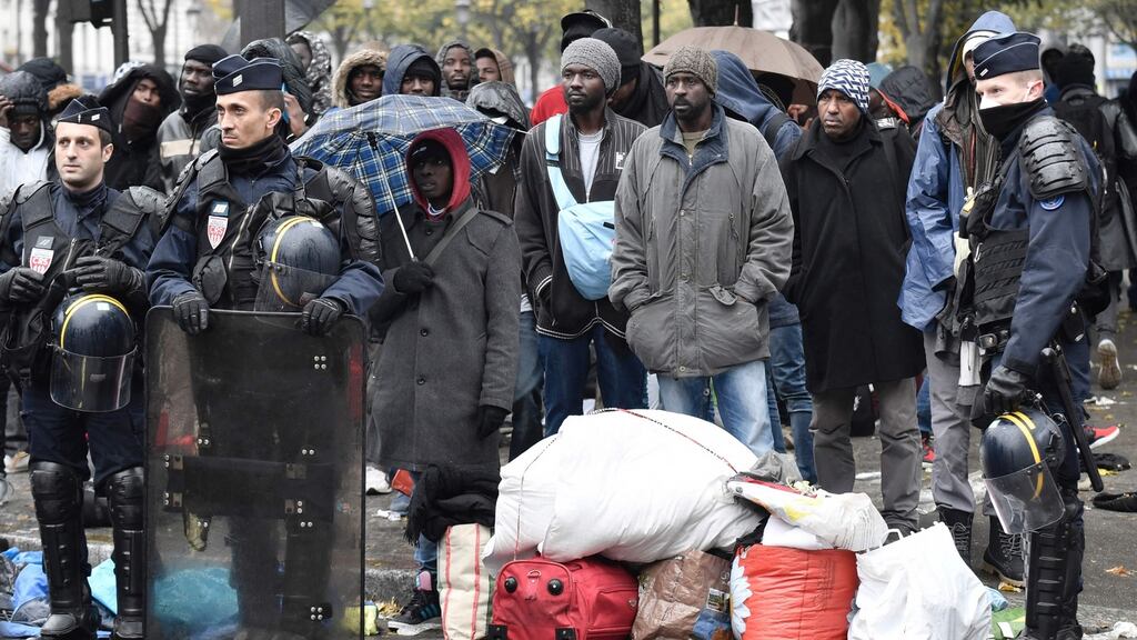 Migrants stand with their belongings near policemen during an evacuation of a makeshift camp near Stalingrad metro station in Paris on Friday. Photograph: Lionel Bonaventure/AFP/Getty Images