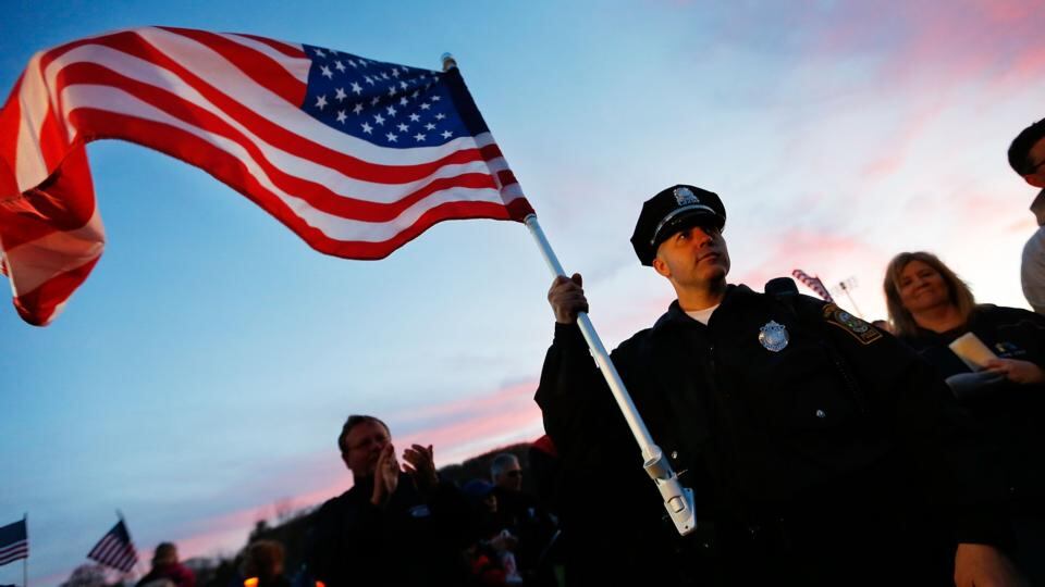Watertown Police officer Brandon O'Neill holds an American flag during a candlelight vigil at Victory Park  in Watertown, Massachusetts last night. Photograph: Jared Wickerham/Getty Images