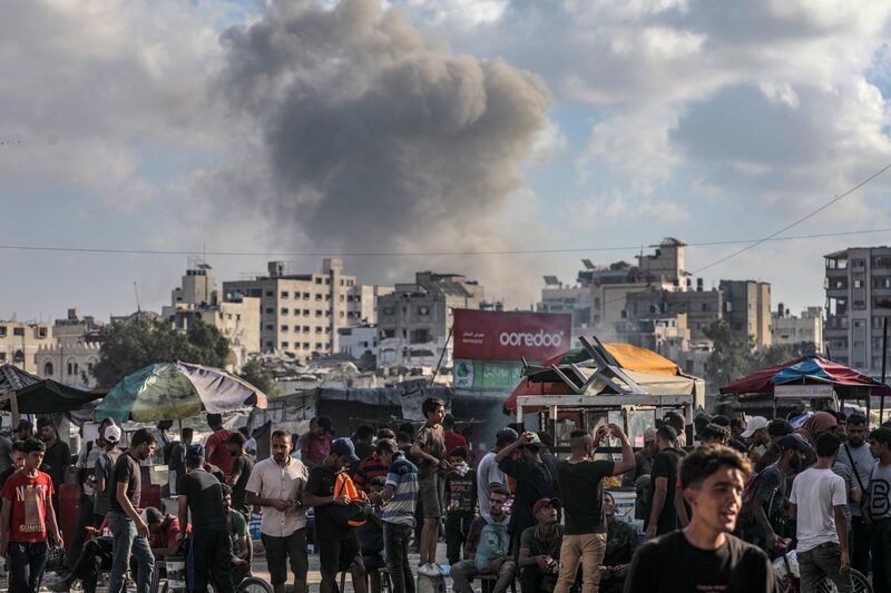 Palestinians gather as the smoke billows following an Israeli air strike on Gaza City. Photograph: Mohammed Saber/EPA
