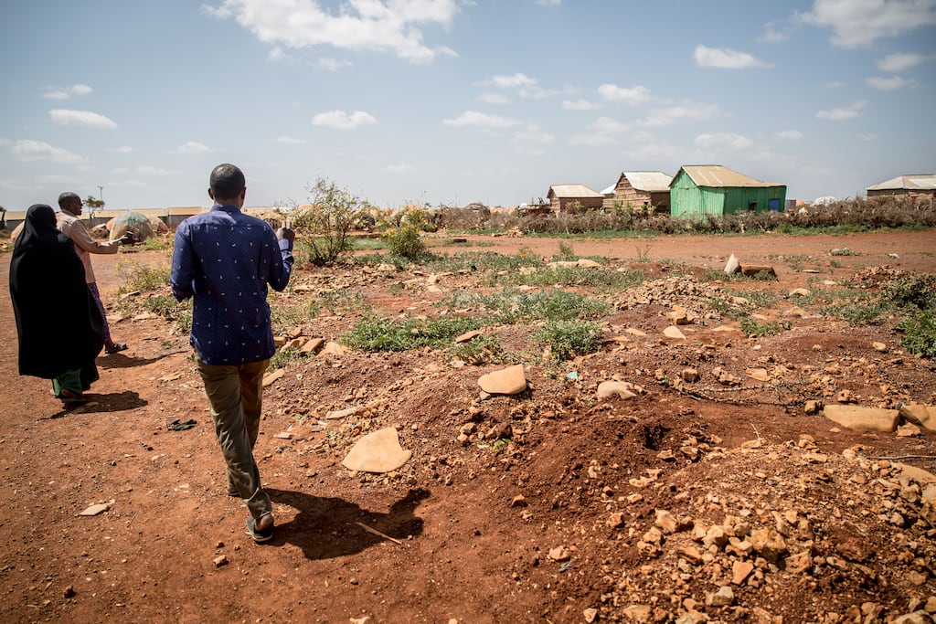 Residents count the mounds of dirt marking the newly dug graves of children in a camp for displaced people in Baidoa, Somalia. Photograph: Sally Hayden