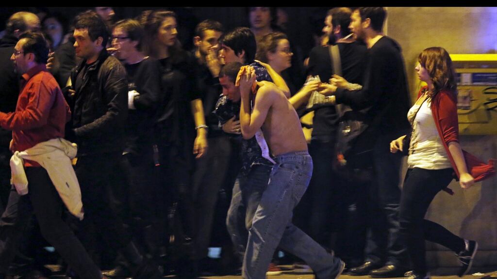 An injured man holds his head as people gather near the Bataclan concert hall following fatal shootings in Paris. Photograph: Christian Hartmann/Reuters