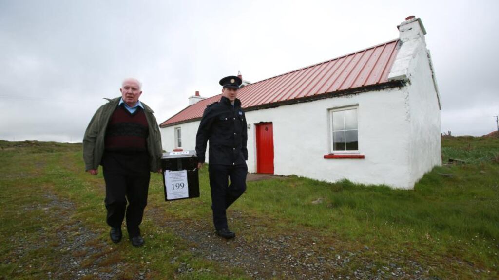 Presiding officer Hugh O’Donnell (left) and Garda officer P.J. McHugh carry the ballot box off the island of Innishfree, Co Donegal.  A local home was turned into a temporary polling station where islanders Phil and Hans Schleweck from Stuttgart, Germany, cast their vote. The rest of Ireland will cast their votes on 23 May. Photograph: Paul McErlane/EPA