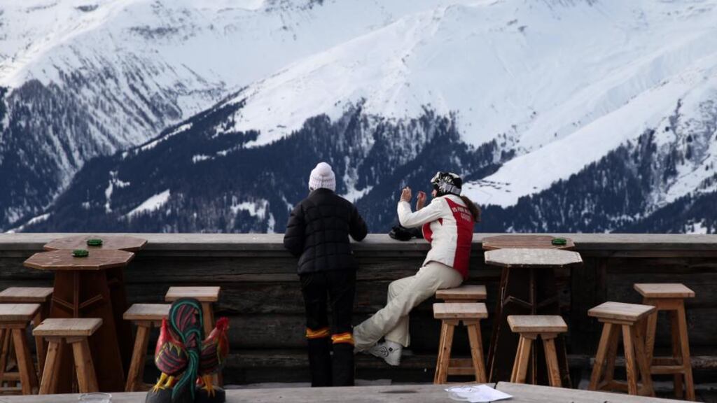 Skiers stop to look over the balcony and down to the town of Davos from the Chalet Gueggel restaurant on the Jakobshorn mountain in Davos, Switzerland. Photograph: Simon Dawson/Bloomberg