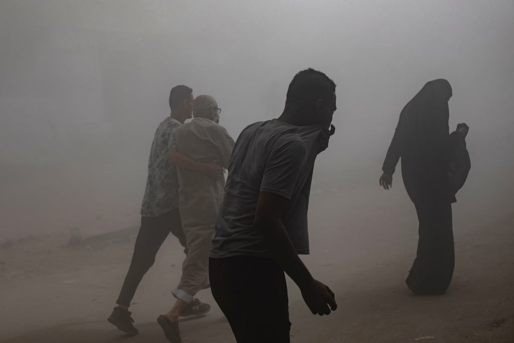 People walk as smoke and dust fill the air after the Al-Ghafari residential tower was hit by an Israeli air strike in Gaza City on Monday. Photograph: EPA