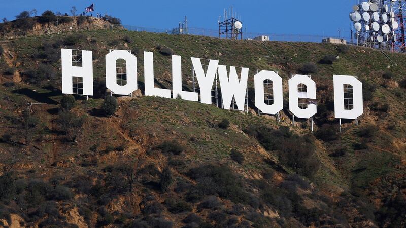 Los Angeles County firemen remove banners from the letters on the Hollywood sign. Photograph:  Damian Dovarganes/AP