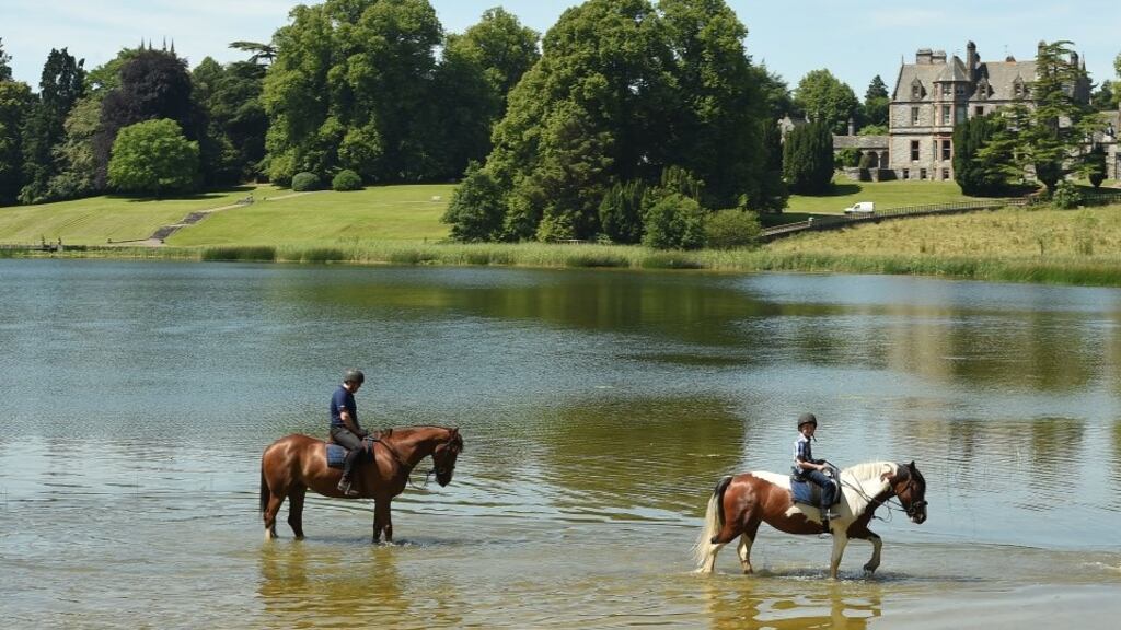 Peter and Turlough McDonnell riding their horses thorugh the lake in front of Castle Leslie