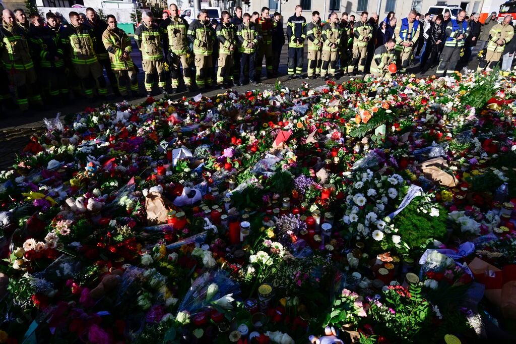 Members of Magdeburg's fire department stand at a makeshift memorial outside the Johannes Church on Sunday, near the site of Friday's attack on a Christmas market. Photograph: John MacDougall/AFP via Getty Images
