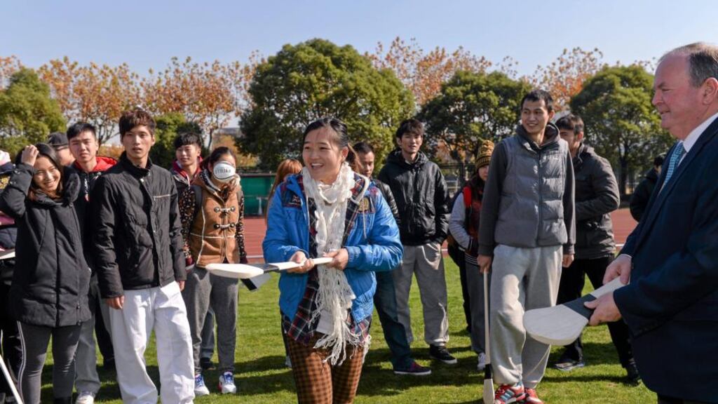 GAA president Liam Ó Néill helps Shanghai student Long Wang Fei come to grips with a hurley