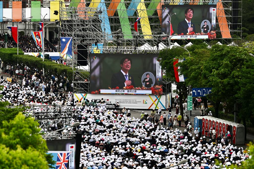 People gather to watch monitor screens showing new President Lai Ching-te delivering his speech in Taipei. Photograph: Taipei news photographer via AP