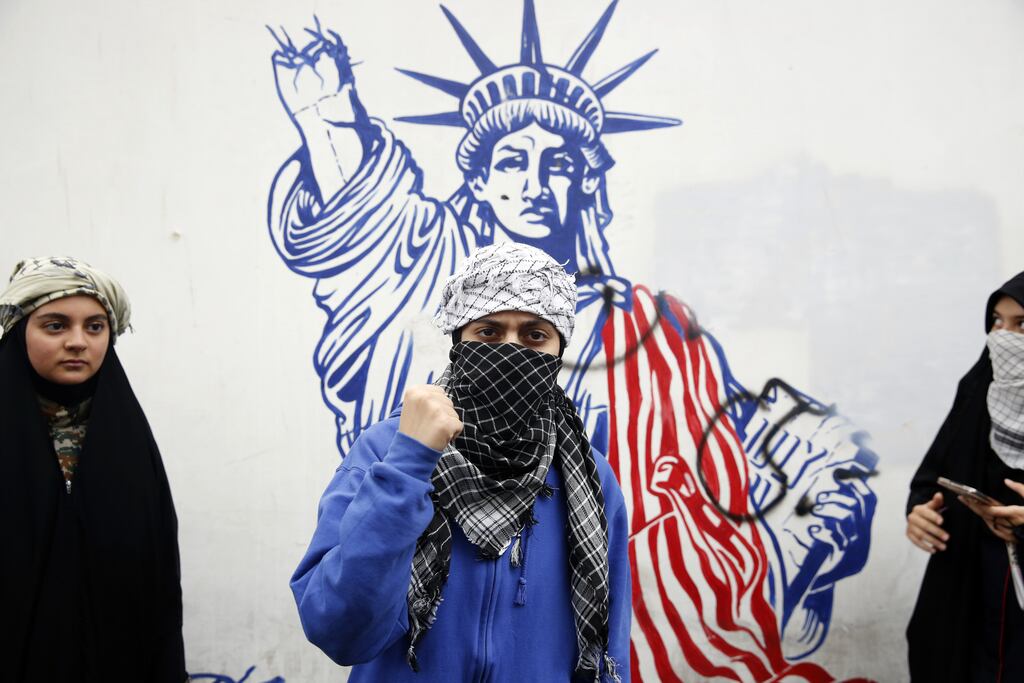 Iranian students pose in front of a mural during an anti-US rally in 2023 marking the 44th anniversary of the US embassy takeover in Tehran, Iran