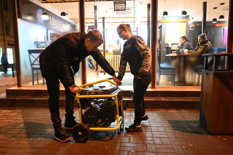 Employees check a power generator standing outside a cafe in Lviv during a blackout. Photograph: Yuriy Dyachyshyn/AFP via Getty Images