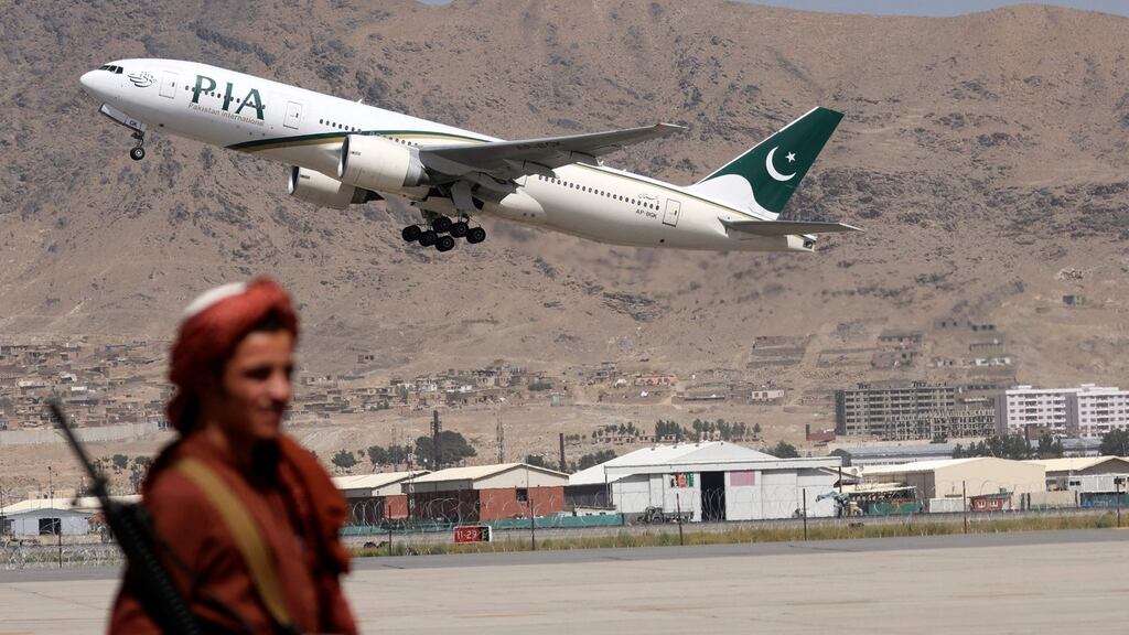 A Taliban fighter stands guard as a Pakistan International Airlines plane, the first commercial international flight to land since the Taliban retook power last month, takes off with passengers onboard at the airport in Kabul on September 13th. Photograph:  Karim Sahib/AFP via Getty Images