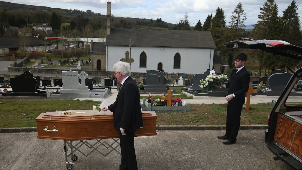 Funeral director Pat Blake places a white rose on the coffin of Anne Best, Co Fermanagh’s first coronavirus victim, at St Ninnidh’s Cemetery in Derrylin. Photograph: John McVitty