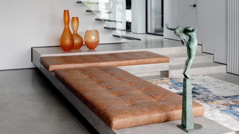 In the adjacent living area, a cantilevered concrete sofa is upholstered in tan leather cushions by Brian Kinsella. Photograph: Ruth Maria Murphy