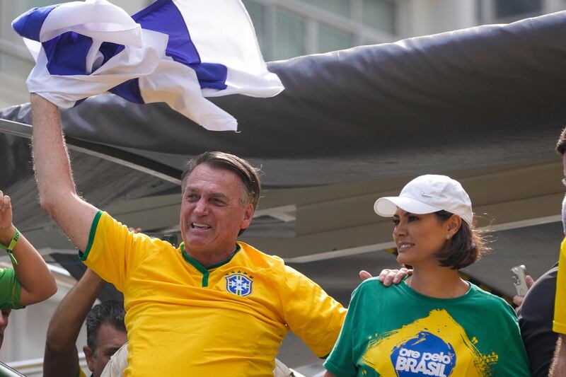 Jair Bolsonaro waves an Israeli flag as he addresses supporters, with his wife, Michelle. Photograph: Andre Penner/AP