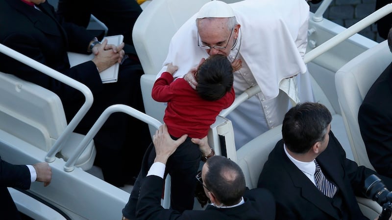 Pope Francis kisses a child as he arrives in Saint Peter's Square for his inaugural mass at the Vatican this morning. Photograph: Tony Gentile/Reuters
