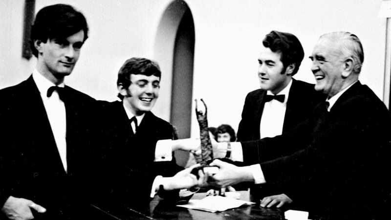 Michael McInerney presenting the trophy to the winning L & H UCD team,  Neal Clarke (left) and Donal O’Riain at the Irish Times debate in 1970. Second from right is the USI debating organiser Roderick Buckley. Photograph: Tommy Collins/The Irish Times