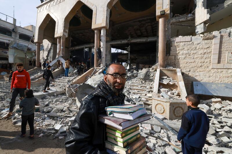 A man walks with salvaged religious books as people inspect the rubble of a mosque in Rafah, Gaza, on Monday following Israeli bombardment. Photograph: Mohammed Abed/AFP via Getty Images