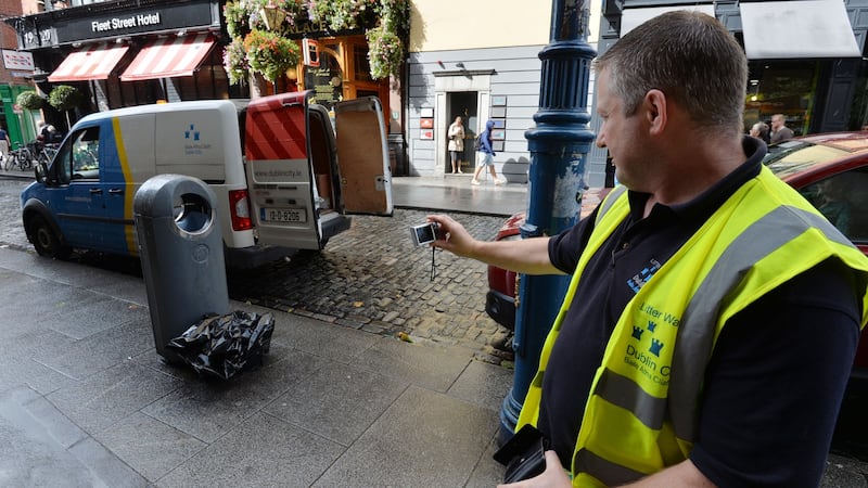 Dublin City Council Liter Warden Darren Hendrick finds a bag of rubbish deposited alongside a bin on Dublin’s Fleet Street. Photograph: Alan Betson/The Irish Times