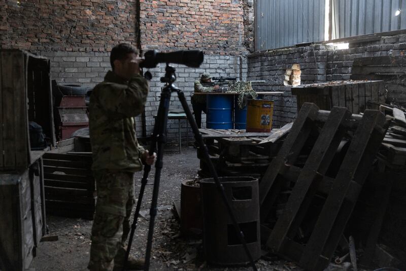 A sniper who uses the call sign Bart, in background, trains his weapon on a Russian position while another soldier spots potential targets with a scope, in southern Ukraine. Photograph: David Guttenfelder/New York Times