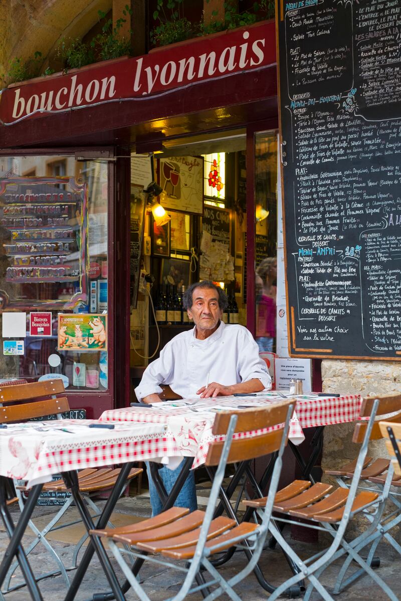 A chef takes a break at the entrance of a typical Bouchon Lyonnais in the Old Town of Lyon. Photograph: Getty